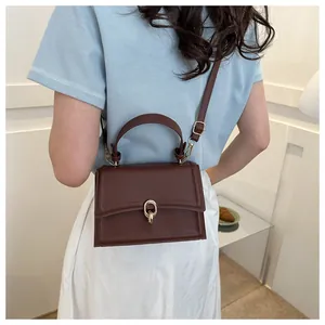 Detail of dark brown retro crossbody bag featuring golden oval buckle and fine leather texture