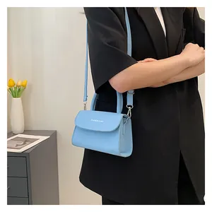 Light blue crossbody bag with white lettering shown on black blazer for commute
