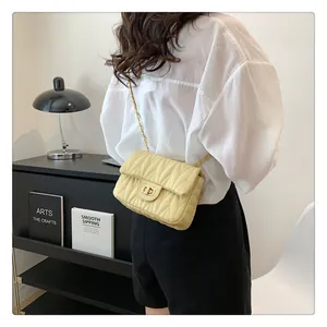 Close-up of quilted light yellow leather chain bag with elegant wave stitching and metal lock