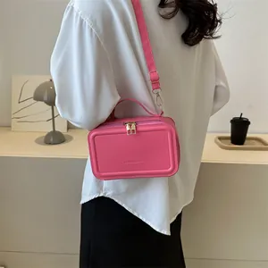 Bright pink leather handbag with double zippers and detachable strap in a modern setting