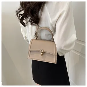 Detail shot of a beige minimalist crossbody bag with golden metal buckle on a model