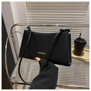 Détail du sac baguette noir avec texte FASHION jaune et bandoulière à nœud