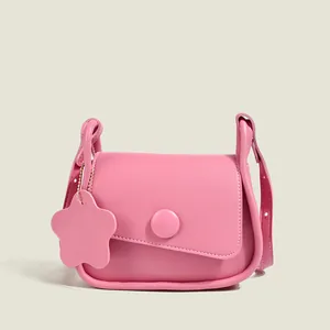 Pink minimalist crossbody bag with asymmetrical flap and leather flower charm detail