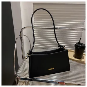 Détail du sac baguette en cuir noir avec logo FASHION doré et anse avec nœud décoratif