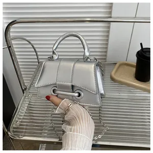Détail macro du mini sac argenté métallisé avec base incurvée et boucle à œillet