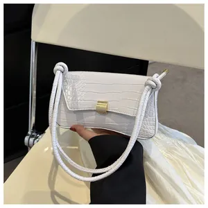 Gros plan du sac à bandoulière blanc motif crocodile avec fermoir doré et bandoulières nouées