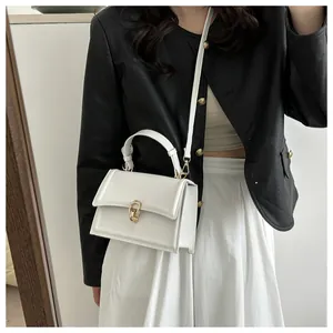 Detailed close-up of white crossbody bag with gold interlocking ring buckle and top handle