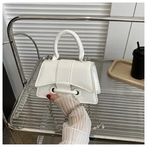 Détail d'un sac à main blanc en cuir avec anneau argenté et bandoulière chaîne