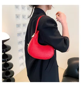 Red crescent moon bag with crocodile texture worn by model in minimalist setting