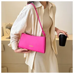 Détail du sac baguette rose fuchsia avec bandoulière à nœud et logo mode embossé