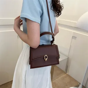 Vintage brown leather crossbody handbag with gold buckle shown on a model