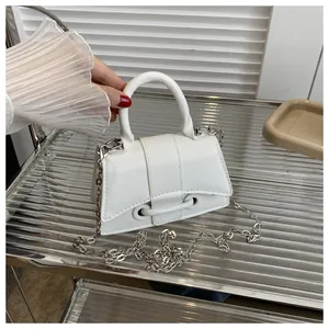 Détail d'un sac carré blanc minimaliste avec chaîne argentée sur support métallique