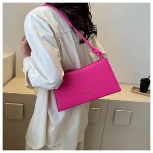 Détail du sac baguette rose vif avec bandoulière à nœud et lettrage de mode
