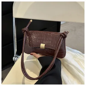Détail du sac baguette marron texture crocodile avec boucle dorée et bandoulière nouée