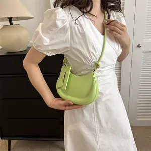 Grüne Halbmond-Tasche mit kleinem Beutel und dünnem Riemen an einer eleganten Frau