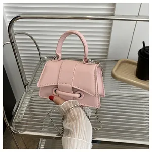 Détail du sac à main trapèze en cuir rose avec bandoulière chaîne et œillets métalliques