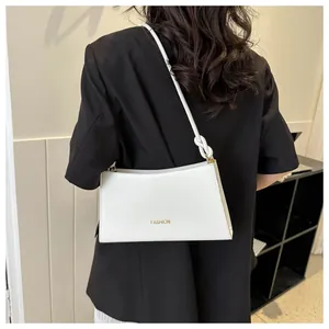 Détail d'un sac baguette blanc en cuir avec bandoulière nouée et logo doré fashion