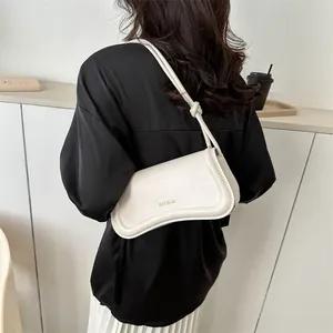 Minimalist beige baguette shoulder bag with adjustable knotted strap on a female model