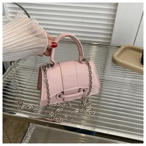 Détail du sac bandoulière rose avec boucle ronde et chaîne argentée sur étagère