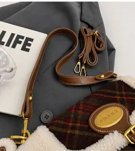 Detail of retro green plaid shoulder bag with plush white fur trim and golden logo plate