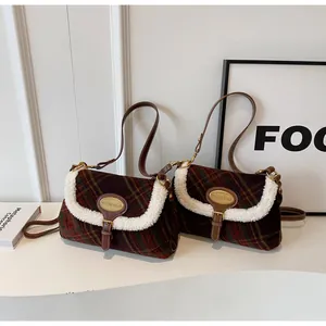 Detail of plaid shoulder bag featuring faux shearling trim and brown leather strap