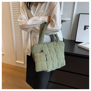 Light green quilted tote bag with matching small pouch worn on the shoulder