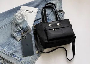 Detail der schwarzen Nylon-Eimertasche mit Augenstickerei und Umhängeriemen