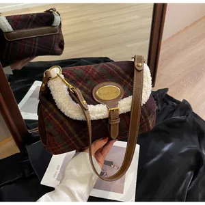 Detail of plaid wool fabric, faux fur trim and gold metal logo on the retro shoulder bag