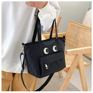 Details der schwarzen Nylon-Eimertasche mit Cartoon-Augen-Design und Goldbeschlägen