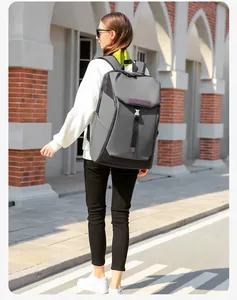 Side view of large waterproof grey travel backpack with buckle straps on a model in the street