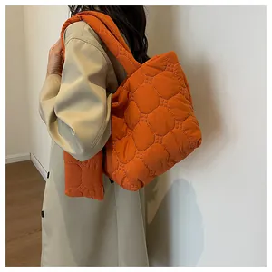 Detail view of large orange quilted tote bag with matching puffy pendant charm