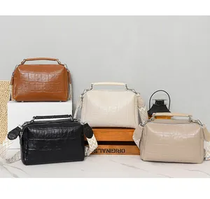 Three crocodile-embossed pillow bags with decorative wide straps in diverse colors