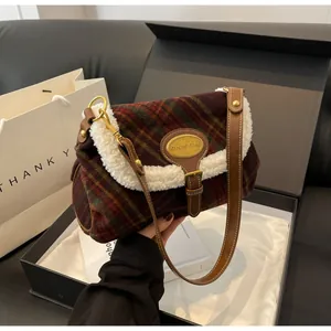 Detail of red and green plaid shoulder bag with soft white faux fur trim and gold buckle