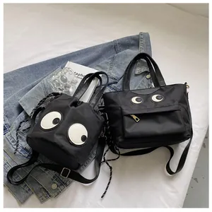 Detail der schwarzen Nylon-Kordelzugbeutel und Tote mit verspielten großen Augen-Patches