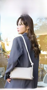 Sac à bandoulière tissé beige avec larges lanières en corde sur un blazer gris