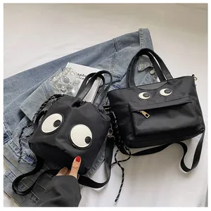 Detailansicht der schwarzen Nylon-Beuteltasche und Tote mit Cartoon-Augen-Mustern auf Stoff