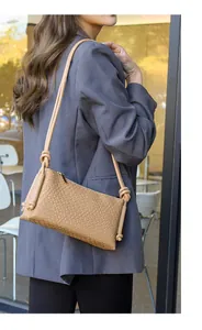 Détail de la texture tissée marron clair et du nœud sur la bandoulière du sac rétro chic