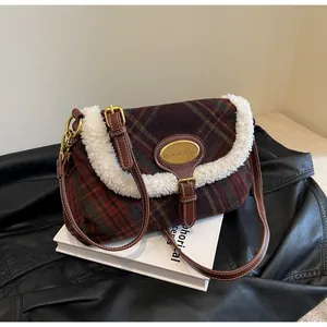 Detail of plaid crossbody bag featuring white faux fur trim and gold logo plaque
