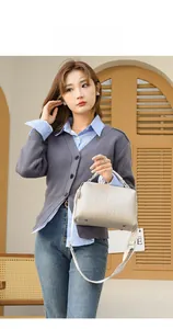 Detail of crocodile embossed crossbody bag with wide strap on grey knit cardigan