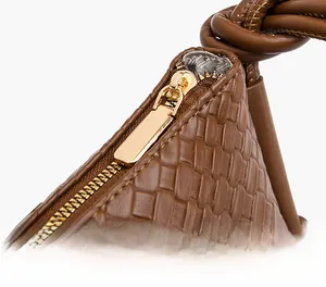 Détail de la fermeture éclair dorée sur le sac en cuir tressé marron vintage