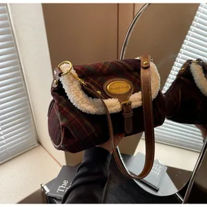 Detail of plaid shoulder bag with fleece trim and gold logo plaque on autumn fabric