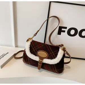 Detail of plaid wool crossbody bag with sherpa trim and golden metal logo tag