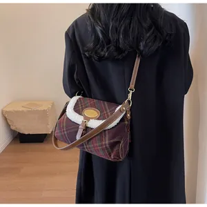 Detail of red plaid shoulder bag with faux shearling trim and brown leather strap