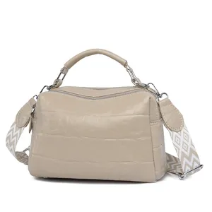 Beige crocodile embossed Boston bag with wide patterned shoulder strap on white backdrop