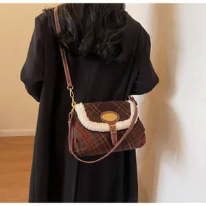 Detail of red plaid wool flap bag with faux shearling trim on a black coat back