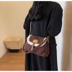 Detail of British plaid crossbody bag with white fleece trim and gold logo plaque