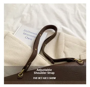 Detail view of the adjustable dark brown leather shoulder strap with golden metal buckles