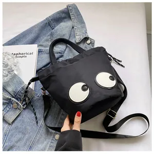 Detailaufnahme der schwarzen Nylon-Beuteltasche mit großen Augen und Kordelzug-Details