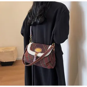 Detail of retro plaid shoulder bag with faux shearling trim and golden metal logo plate