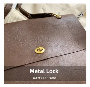 Close-up of golden hardware lock and textured vintage brown leather on the tote bag